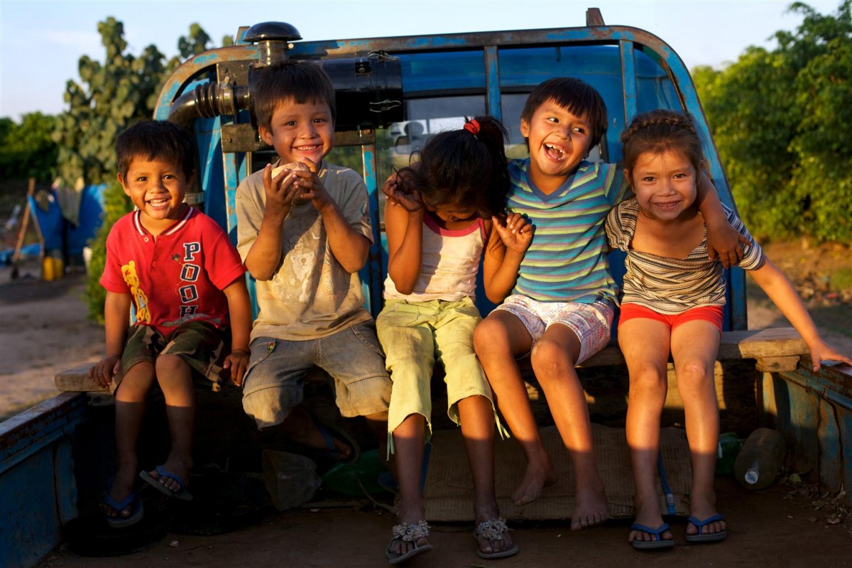 Children laugh, sitting in the back of a flat-bed truck in a cane field where their parents are working, near their home village of San Juan del Carmen. The truck is used to take villagers and their children to and from the fields. The children spend most of their day playing, but sometimes help their parents work. Although children in the village no longer have to work in the fields, many help their parents plant cane or clear the fields to supplement the family income.

In June 2011 in Bolivia, legislative reforms and government efforts in health, education and other basic social services are improving the lives of children and families. Nevertheless, over half of the countrys 10.4 million people  more than 40 per cent of whom are children  live in poverty, with 26 per cent living in extreme poverty. An estimated 310,000 children work, sometimes in dangerous conditions, to help support their families. Tens of thousands of children, some as young as six years old, have traditionally worked in the sugar cane harvest and in mining, the two harshest jobs in the country. Children working in the sugar cane harvest also frequently drop out of school. Over the past decade, however, the number of children working in the sugar cane harvest has dropped from 8,000 to less than 1,000 thanks to initiatives providing stable schools and basic infrastructure in communities. For example, the impoverished village of San Juan del Carmen in the eastern department of Santa Cruz, now has permanent schools and teachers. The village is surrounded by cane fields and has no electricity, but residents live in their own homes  instead of in temporary harvesting camps on the lands where they work. And its children attend school, as well as work part-time to help their families. Two of the villages four schoolhouses have been built with support from the regional government and UNICEF, which has also helped install a well and build a football pitch there. UNICEF and its partners
