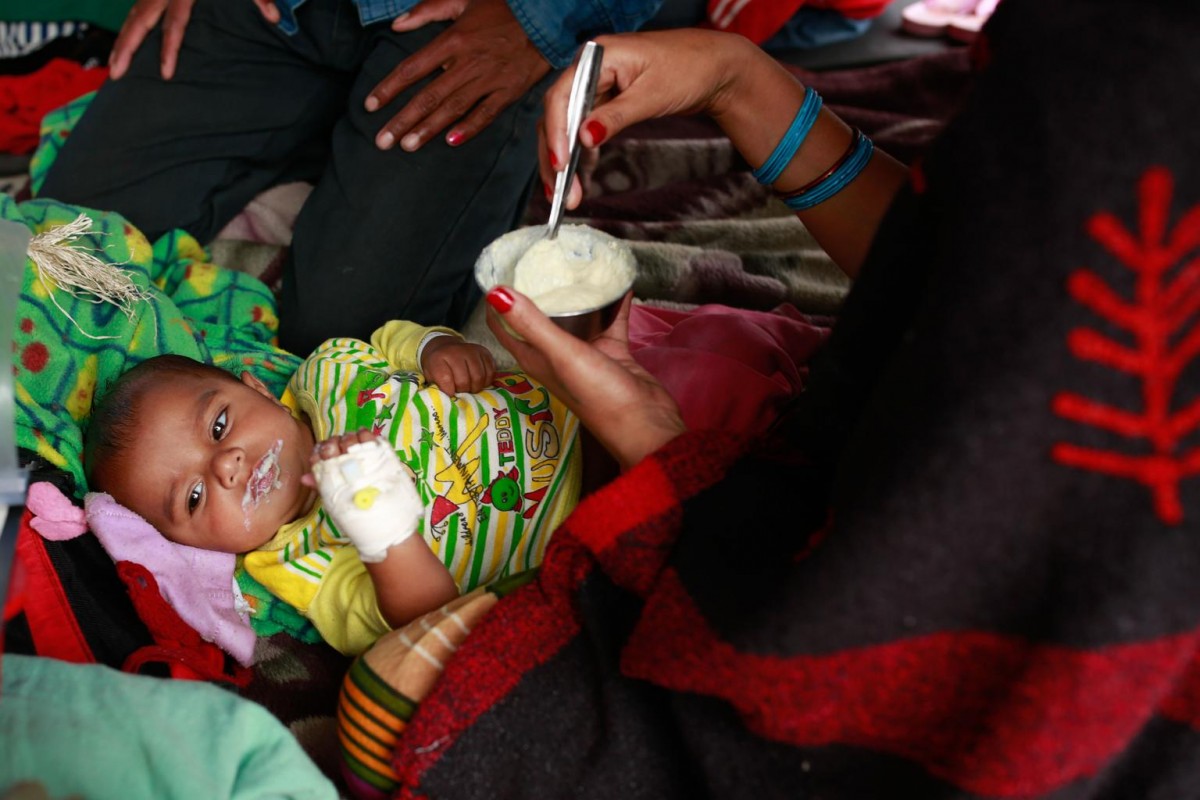 On 26 April, a woman feeds her infant, who was injured during the massive earthquake, at Tribhuvan University Teaching Hospital in Kathmandu, the capital.

On 28 April 2015 in Nepal, search, rescue and relief operations continue in the aftermath of the massive 7.8 magnitude earthquake that hit the country on 25 April. The quakes epicentre was 80 kilometres from Kathmandu, the capital. At least 3,351 people have been killed, 6,833 have been injured, and 8 million people in 39 districts have been affected. The Government has declared a state of emergency in 35 affected districts in the country, where more than 1.3 million people  over half of whom are children  are affected by the disaster. Homes and vital infrastructure, including hospitals, have been severely damaged or destroyed, leaving thousands of children and families homeless, vulnerable and in urgent need of food, shelter, safe water and sanitation, and health support. Over 1.4 million people are in need of food assistance. Most of the displaced are sheltering in camps or in available open spaces. The situation has been exacerbated by continuing powerful aftershocks that have caused additional damage. Working with the Government and other partners, including fellow United Nations organizations, UNICEF is supporting water, sanitation and hygiene (WASH), health, nutrition, child protection, education and other interventions. In response to the disaster, UNICEF is providing hospitals tents, tarpaulin sheeting, emergency medical kits, vaccines and related supplies, zinc and oral rehydration salts to prevent diarrhoeal disease outbreaks, and temporary learning spaces and psychosocial counselling for children. UNICEF is also procuring emergency health kits and is supporting water trucking services in camps for the displaced.