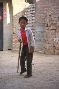 Chen Qitao, an eleven-year-old boy, leans on his walking cane in the village of Xiao Li Huang, in Shandong Province.  Qitao is one of hundreds of victims of a polio epidemic that struck northern China in 1988.  Since 1989 and 1990 when almost 10,000 children fell victim to a polio epidemic, China is now, in 1996, poised to meet the target set by the World Summit for Children in 1990: the complete eradication of the disease by the year 2000.  An intensive media campaign coupled with grassroots mobilization resulted in the immunization of 83 million children in just two days in 1994.  In 1995 there was only one confirmed case of polio in the entire country.  While the Government has taken the lead, UNICEF and NGOs have lent significant technical, logistical and financial support.  The result has been the virtual extinction of a virulent disease in less that a decade.