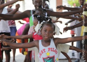 On 23 April, children exercise during a recreation activity at the Parc Jean Marie Vincent sports centre in the Piste Aviation neighbourhood of Port-au-Prince, the capital. The area is serving as a temporary settlement site for an estimated 25,000 people displaced by the earthquake. The recreation programme provides structured daily sports activities, as well as psychosocial support, for young people. It is managed by the Haitian Olympic Committee, with support from the Government, UNICEF and other partners. Most open spaces in the city are now occupied by the displaced.  By early May 2010 in Haiti, emergency responses had shifted to long-term recovery efforts in response to the 7.3 magnitude earthquake that hit the country on 12 January. The quakes epicentre was only 17 kilometres from Port-au-Prince, the capital, more than 222,500 people were killed and 1.3 million, of whom 450,000 were children, became homeless. In Port-au-Prince, more than 619,000 people continue to live in makeshift settlements, despite an exodus of over 604,000 from the devastated city. The towns of Léogâne and Jacmel were also heavily damaged; and social infrastructures in rural communities, which now host some of the displaced, are over-strained. In the capital, major government and private infrastructure have been destroyed or heavily damaged, including hospitals, water, sanitation and electrical systems, and telecommunications, banks and transportation networks. UNICEF is working with the Government, other UN agencies, international and local NGOs and private partners to help rebuild  with special focus on the estimated 46 per cent of Haitis nearly 10 million inhabitants who are under age 18. UNICEF is the lead coordinating agency for nutrition, WASH (water, sanitation and hygiene) and child protection; UNICEF also shares lead coordinating duties on education with Save the Children, and is a key health partner. This latest catastrophe has exacerbated Haitis already critical humanitarian situation. Prior to the quake, more than 78 per cent of the population lived on less than US $2.00 a day. UNICEFs portion of the February 2010 United Nations Haiti Revised Humanitarian Appeal (totalling US $1.44 billion) is US $222.8 million, most of which has been received. But while international donors have pledged some US $5.3 billion to support all aspects of Haitis recovery over the next 18 months, an estimated US $11.5 billion is required to meet projected needs.