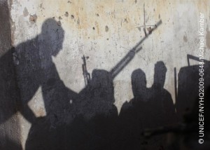 Militia members, holding guns and standing on a truck with a heavy machine gun, cast shadows against a wall in central Somalia. They have been hired by the local government to provide security in the community. Though the immediate area is currently peaceful, nearby hostilities are present a constant threat to stability. By April 2009 in Somalia, drought and armed conflicts had displaced some 1.2 million people, contributing to a nutrition crisis that leaves one in six children under the age of five acutely malnourished. The country remains one of the three poorest in the world, and is the second-worst affected by recent volatility in food prices. Forty-three per cent of the population including 1.4 million children requires humanitarian assistance, but chronic conflict among armed groups limits humanitarian access to vulnerable populations. UNICEF and partners currently provide water to 250,000 displaced people and nutritional support to over 100,000 children per month. Nevertheless, over 300,000 children are expected to experience acute malnutrition over the course of the year. The region worst affected by the drought and conflict is the Central and Southern Zone, where humanitarian aid workers are also being targeted.