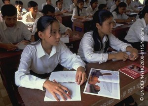 Literature showing the impact of AIDS lying on their desks, adolescent girls and boys listen to a presentation on AIDS awareness and prevention, part of a student-to-student education exchange initiative supported by UNICEF, in a village in the south-eastern province of Svay Rieng.  In 2000 in Cambodia, after more than a decade of intermittent peace, the country is continuing its recovery from 30 years of conflict, including genocide. Despite progress in health and nutrition, maternal and infant mortality rates are the highest in south-east Asia, most of the predominantly rural population still lacks access to essential services, and problems of ongoing violence, displacement and landmines continue to take their toll. HIV/AIDS is spreading rapidly, accelerated by a growing commercial sex industry, with an estimated 35 per cent of sex workers under 18 years of age, almost half of whom are presumed to be HIV positive. With half of the country's population under 18 years of age, these indicators represent a major threat to their future, including increased rates of mother-to-child transmission. UNICEF programmes to help combat the spread of HIV/AIDS include support for prevention and awareness programmes to all social sectors, including student-to-student education exchanges, the provision of testing and counselling services, and improved access to recovery and care for affected children and families.