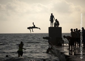 On 10 June, boys dive into the coastal waters of the Mediterranean Sea, in the city of Benghazi.  By 15 June 2011, over one million people had fled the conflict between government and rebel forces in the Libyan Arab Jamahiriya, and an estimated 243,000 had been displaced within the countrys borders. Intense fighting continues, particularly near the cities of Brega and Misrata and in the Nafusa Mountains. United Nations inter-agency missions to Tripoli, the capital, and to Misrata have confirmed that children are experiencing increased stress and anxiety. Conflict zones are also experiencing medicine shortages; UNICEF has delivered vaccines and other medical supplies to some areas in need. In the eastern city of Benghazi, which is controlled by rebel forces, children and their families exist in an interregnum between peace and war. Many have sought refuge from other parts of the country, and many men of these families are away fighting. UNICEF and partners are assisting the provision of safe water in the city and supporting workshops to raise awareness of the risks to children and others of explosive remnants of war (ERW). Child protection workshops are training volunteers to provide psychosocial support to children. Workshops will be expanded to other parts of the country as access to other areas is restored. Most formal education has been halted since the onset of the crisis. In Benghazi, UNICEF is working to provide recreational and educational activities for children. The mass exodus from Libya  including over 550,318 people who have escaped to Tunisia and over 347,900 who have fled to Egypt  has also created emergency conditions in neighbouring countries. To address the regional crisis, a joint United Nations flash appeal for US$407 million has been issued; UNICEFs portion of the appeal is US$20 million.