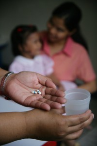 A health worker holds ARV medications and a glass of water in her hands at a child care centre in Tondo, a neighbourhood of Manila, the capital. Behind her, an HIV-positive child sits with a caregiver. The centre is run by Precious Jewels Ministry, a UNICEF-assisted centre NGO that offers medical assistance, educational activities and counselling for AIDS-affected children, as well as community outreach to raise awareness of HIV/AIDS and combat the stigma associated with the disease.  In 2006 in the Philippines, HIV transmission is hidden and growing. While official statistics cite fewer than 10,000 HIV cases nationwide, high-risk behaviours, especially among adolescents, are on the rise. Those at highest risk are children in depressed, urban areas, those who live or work in the streets and those involved in the sex industry. Many have limited access to basic services like education, community support and health care. And a strong culture of stigma, denial and silence has prevented an open discussion of HIV/AIDS, sexuality and adolescent reproductive health. Other factors impeding prevention and care services include limited knowledge and skills among health-care workers; rapid turnover and migration of staff; and disruption of health systems due to emergencies and conflict. On Mindanao Island, a decades-long conflict between Christians and Muslims has killed, injured or displaced thousands of children, and left others vulnerable to abduction, trafficking and abuse. Working with government, NGO and other partners, UNICEF supports peer counselling and prevention awareness training for adolescents; expanded voluntary counselling and testing services; and treatment, care and support services for children infected with HIV/AIDS. UNICEF also supports child protection, peace building and the delivery of social services in conflict areas.