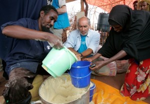 Gérard Bocquenet, Executive Director, French National Committee looks at an internally displaced woman receiving food at a wet feeding centre run by a local NGO and suppored by UNICEF during a visit by UNICEF National Committee members near Wajir town in North Eastern Kenya, September 2; 2011. Photo by Antony Njuguna/UNICEF