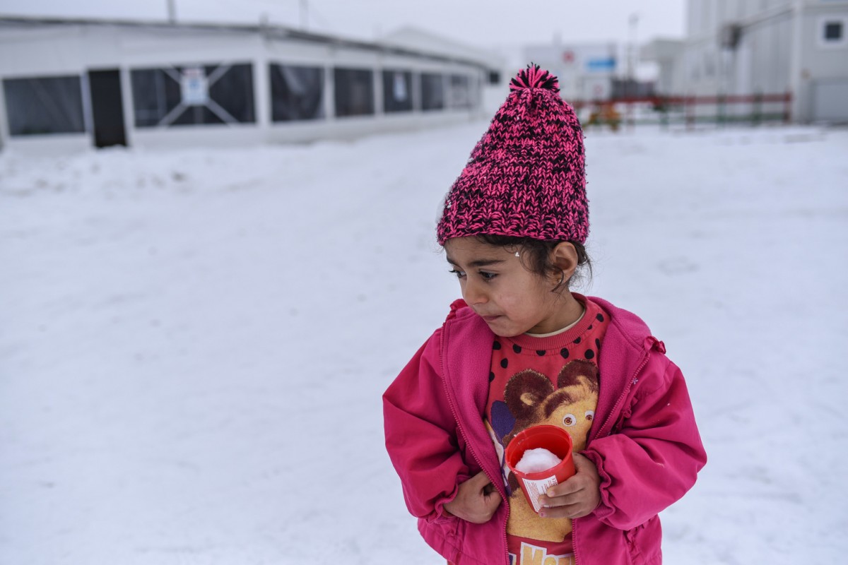 On 18 January 2017, in the Tabanovce refugee and migrant centre, a Syrian girl, carrying a plastic cup filled with snow, contemplates whether to join outdoor activities considering the freezing weather. 

The Tabanovce refugee and migrant centre is currently home to some 100 refugees and migrants - a third of them children. Most have been living in the centre since the closure of borders along the Balkan route in March 2016.  UNICEF has provided ongoing support to preserve some semblance of normalcy for children trapped in an abnormal situation - supporting safe spaces for children to play and learn and psychosocial, health and nutrition support. The maths classes are part of the UNICEF supported transitional learning opportunities for school-aged children to help them integrate back into formal education in their final destinations, or into the local school system, should their families decide to apply for asylum in the country.

In January 2017, in Greece and the Balkans, migrants and refugees from different parts of the world  including many infants and young children  remain stranded. Many are being housed in shelters that are ill-equipped for winter, even as temperatures fall as low as -20 Celsius. With no sign of a let-up in the extreme cold weather and storms sweeping Eastern, Central and Southern Europe, refugee and migrant children risk falling sick from respiratory and other serious illnesses. Overcrowding and poor insulation make the shelters particularly unhealthy, and allow respiratory diseases to spread quickly when cold weather hits. According to the WHO, the seasonal influenza season started earlier this year in Europe. 

In a number of affected countries, including Croatia, Serbia, Slovenia and the former Yugoslav Republic of Macedonia, UNICEF and its partners are monitoring the situation of children and women and responding as needed. UNICEF is also distributing winter clothing and other essential items for women and children, using mobile