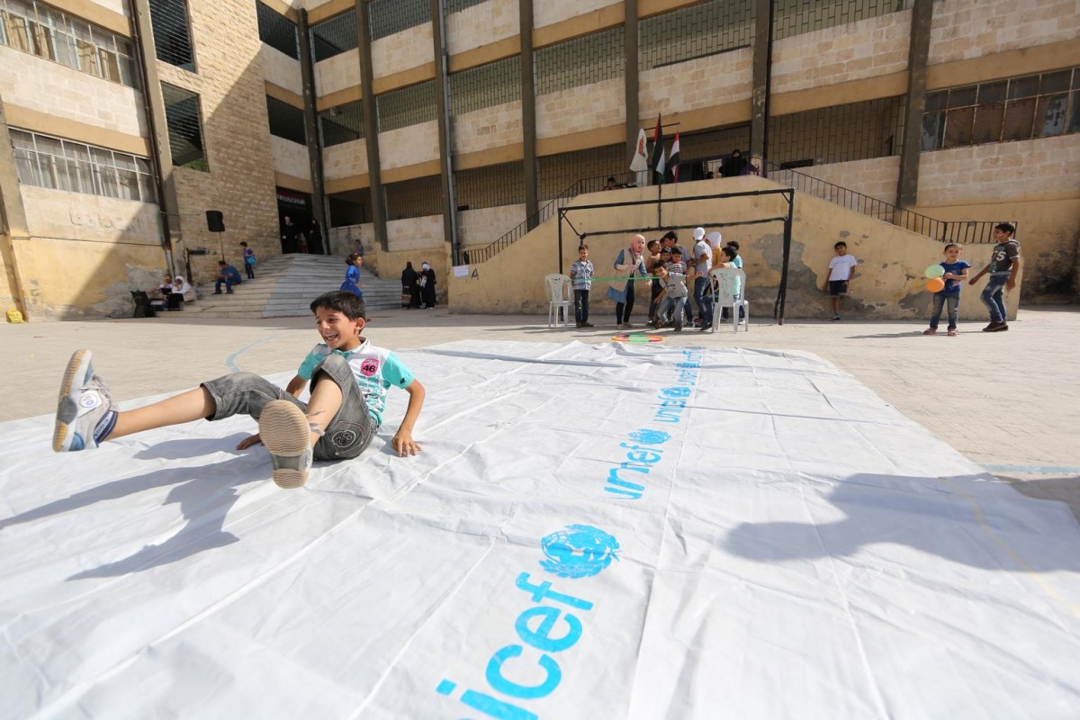 On 14 September 2015 in the Syrian Arab Republic, (foreground) a boy is among children playing outdoors during a recreational period at UNICEF-supported Mahmoud Tayfor School in the Al-Akramia area in Aleppo City, on the first day of school.

As other children around the world return to school, more than 2 million in the Syrian Arab Republic will not be able to join them. Another 400,000 in the country are at risk of dropping out of school as a result of conflict, violence and displacement. Still others have lost up to four years of schooling, and some children have never been inside a classroom. An estimated 5,000 schools across the country are not providing education  because they have been destroyed or damaged, are sheltering displaced families, or have become bases for armed forces or armed groups. A UNICEF-supported Back to Learning campaign under way in the country targets 2.2 million children and includes the distribution of school bags being produced by local suppliers.