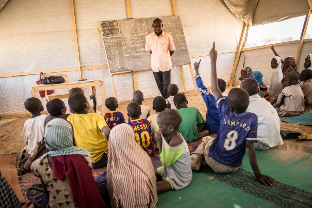 On 14 April, Abba Kaka Sani (centre, standing) teaches class in a temporary learning space in the Dar es Salam camp in the Baga Sola area, in the Lake Region. More than 4,900 Nigerian refugees currently sheltering in the camp, where UNICEF has set up 16 temporary learning spaces and has provided teaching materials and school supplies, as well as other educational support for children.

By mid-April 2015, more than 18,800 Nigerians had sought refuge in Chad to escape the continuing crisis in their homeland. Many of them had travelled for days, on foot or in small canoes and fishing boats across Lake Chad, to reach safety. All continue to face hardships, with children at increasing risk of falling ill from disease. There is also a risk of continued violence because of the close proximity to Nigerias border. The large number of refugees is also straining already weak infrastructure and services in host communities overwhelmed by the influx. Working with the Government of Chad and other partners, UNICEF is supporting health, nutrition, water, sanitation and hygiene (WASH), education, child protection and other interventions, including the setup of child-friendly spaces to provide psychosocial support for vulnerable children  many of whom have lost or become separated from family members and have witnessed violence and atrocities. UNICEF is seeking US $63.1 million to meet projected emergency needs in the country for 2015, including for refugee and displaced children and their families, and host communities.