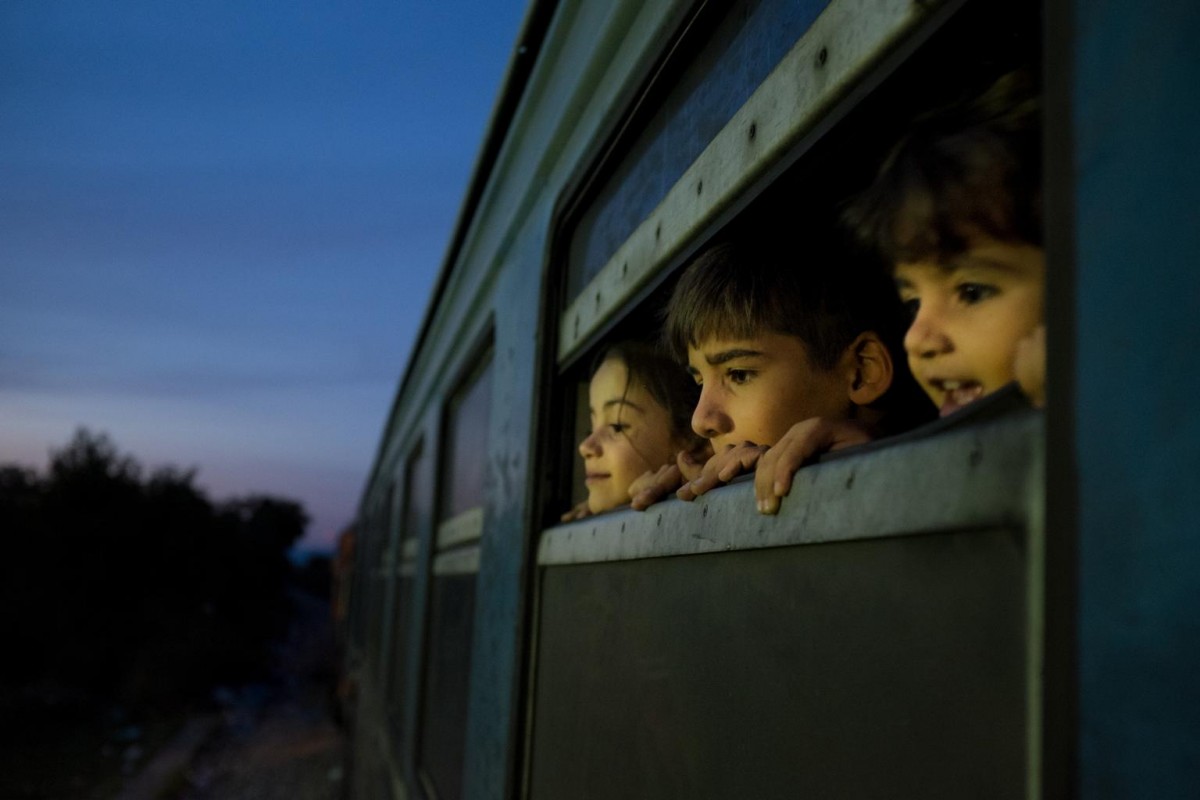 On 2 October 2015 in the former Yugoslav Republic of Macedonia, three children look out of the window of a train as refugees primarily from the Syrian Arab Republic, Afghanistan and Iraq board the train at a reception center for refugees and migrants, in Gevgelija. From here refugees board a special train that takes them Tabanovce close to the border with Serbia.

In late September 2015 in the former Yugoslav Republic of Macedonia, more than 96,800 people have been registered at the border by police near the town of Gevgelija, after entering from Greece, since June 2015.  As many as 42,299 people, of whom 35% were women and children have been registered since 1 September.   It is estimated that just as many are transiting without being registered.  The latest Government Response Plan issued in September indicates that as many as two thirds transit through the country without being registered. Many are escaping conflict and insecurity in their home countries of Afghanistan, Iraq, Pakistan and the Syrian Arab Republic. There are children of all ages traveling with their families. Some are unaccompanied minors aged 1618 years who are traveling in groups with friends. They are arriving in the country from Greece, transiting to Serbia and further to Hungary, from where they generally aim to reach other countries in the European Union.