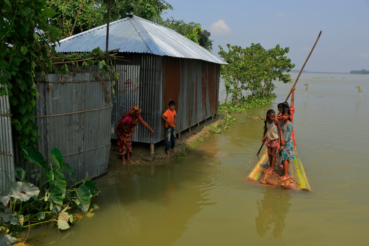 On 17 August 2017, people using a boat made out of a banana tree makes their way to a flood shelter in Kurigram District is located in the Rangpur Division, in Northern Bangladesh.

In August 2017, according to the Ministry of Disaster Management and Relief (MoDMR), an estimated 3.9 million people in 20 districts of Bangladesh have been affected by flooding, the second round of exceptionally heavy monsoon rains to hit the country. Flood barriers have been breached in Saidpur, Lalmonirhat, Dinajpur, Kurigram, Rajshahi and Badarganj. According to the Bangladesh Flood Forecast and Warning Centre (FFWC) 21 rivers are still flowing above the pre-established danger level, and the waters of the Brahmaputra-Jamuna and Ganges-Padma Rivers are still rising. Access to affected areas is challenging, as flooding in the north has made the railway inoperable and roads difficult to navigate, while the runway at Saidpur airport is at risk of being submerged.

As of 14 August, 89 people are known to have died, including at least 14 people in the last 24 hours. 1,392 shelters in flood-affected areas are currently sheltering more than 282,479 people. An estimated 1,000 schools in Districts of Lalmonirhat, Panchagarh, Nilphamari, Kurigram, Gaibandha, Bogra, Jamalpur, Tangail, Sunamganj and Sylhet have closed because they have been flooded or are being used as temporary shelters. An estimated 110,400 hectares of cultivated land have been affected. According to the Department of Public Health Engineering (DPHE), a total of 12,719 tube-wells have been submerged in Kurigram District alone leaving people without easy to access to potable water. Affected children and their families need temporary shelters, access to food and safe drinking water and sanitation.