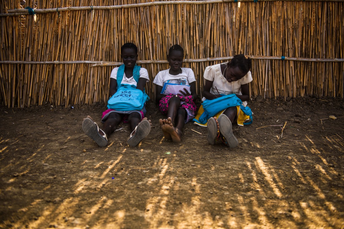Girls sit on the ground after school at the Upper Nile primary school in the Protection of Civilians (PoC) site in Bentiu, South Sudan, Monday 1 May 2017.

As of May 2017, the United Nations’ protection of civilians (PoC) site in Bentiu, Unity State, is home to more than 120,000 internally displaced South Sudanese. Surrounded by war and famine, children and their families are seeking safety in the PoC from armed groups involved in the ongoing conflict across the country. The displaced are forced to live in overcrowded conditions and are reliant on international aid organisations for the basics like food and sanitation. 

Around 60 per cent of those displaced are under 18 years of age and it is estimated that more than 33,000 children are attending UNICEF supported schools in the PoC. Schools such as Upper Nile School cater for the huge youth population, but classes are overcrowded. With upwards of 70 children per classroom and educational resources scarce, UNICEF and its partners are working to improve access to education through the provision of basic education supplies, as well as training and allowances for volunteer teachers.

For those attending classes at the Upper Nile School, classes offer some respite from the ongoing war. Insecurity, ongoing displacement and attacks on schools mean that nearly three quarters of the country’s children are out of school — the highest proportion of out-of-school children in the world. 

Education is central to the humanitarian response for those living in PoCs across South Sudan. Many have witnessed unspeakable horrors and suffer the trauma associated with war. Education is one ray of light shining through the cracks of their young country.