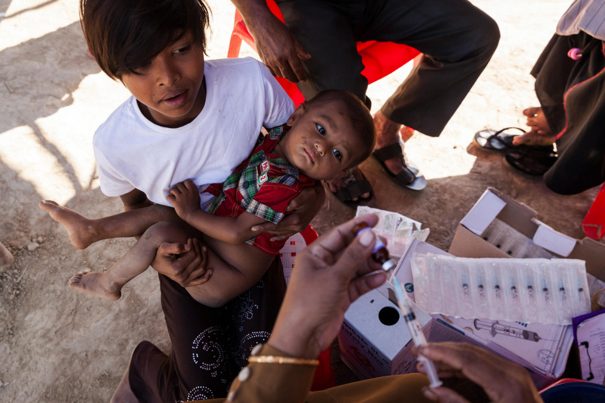 On 30 November 2017 in Bangladesh, a young woman and a baby waiting to be immunized watch as a health worker fills a syringe with vaccine, in the Unchiprang makeshift Rohingya refugee camp in Cox’s Bazar district during the UNICEF-supported measles vaccination campaign.

Since late August 2017, some 625,000 Rohingya have fled from Myanmar to neighbouring Bangladesh to escape the violence in their homeland. More than half of them are children – many in dire need of vital support. Up to 348,000 children under the age of 15 are estimated in need of urgent health services. With crowded living conditions and a severe lack of adequate water and sanitation, the risk of communicable disease outbreak – including cholera and measles – remains very high. The risks of vaccine-preventable diseases are also high among the Rohingya population, where immunization coverage is low. As of 18 November, the number of measles cases has reached 1,714, with two fatalities recorded. In response to the measles outbreak, a 12-day mop-up measles/rubella (MR) campaign targeting 336,943 children 6 months to 15 years old, and involving more than 100 teams, was initiated that same day. By 29 November, 97 per cent of the children (325,457) had been immunized. To ensure that the remaining children are reached, the campaign has been extended for three additional days to conduct mop-up+ vaccination activities that begin on 5 December 2017. UNICEF continues to provide integrated primary-health-care services and has reached over 21,550 children under-5 and pregnant women through outpatient consultations by partners during the past two months.