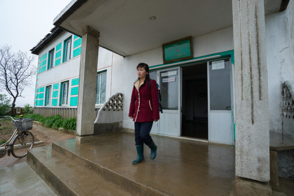 17 May 2018, Hwasan Ri, DPR Korea: For 9 years, Dr. Ri Chol Ok - pictured leaving her village clinic - has been trekking door to door to bring health care to the homes of families in a remote area of DPR Korea. “I cover 122 households, and in a single day I visit 20 to 30 families,” she explains. It’s not an easy job, she says, but thanks to a new bag provided by UNICEF, her work has become a little easier. “The bag is full of essential medical equipment and medicines which we commonly use, like antibiotics and oral rehydration salts (ORS),” says Dr Ri while checking the blue rucksack in preparation for her home visits today. “Before, we mostly used herbal medicines – it’s much better now.” In rural areas like this, children can be particularly vulnerable to diseases and illnesses. Rates of malnutrition and other related problems tend to be higher in rural areas and this year alone six children have been identified in this village. “It’s important to treat children with diarrhoea quickly and this bag allows us to deliver care to children fast,” she says before heading off to begin her shift for the day. “Today I’m first visiting two homes to check on children who had diarrhoea,” she says. “They’ve been treated and should be ok now, but I just want to check their status.” Dr. Ri leaves the clinic and quickly marches down a hill in her boots. It’s a relatively small village of less than 4000 people dispersed across the countryside. The first stop is to the home of 1-and-a-half-year-old Ri Song. “She had diarrhoea for two days and it didn’t stop,” explains her mother while Dr Ri checks the baby’s health. “We were given ORS and zinc tablets and after two days she’s better again.” Globally, diarrhoea is the second leading cause of death for children under five. Without the quick response and right medication provided by Dr Ri Chol Oh, children like young Ri Song would be a great risk. In addition to the bag