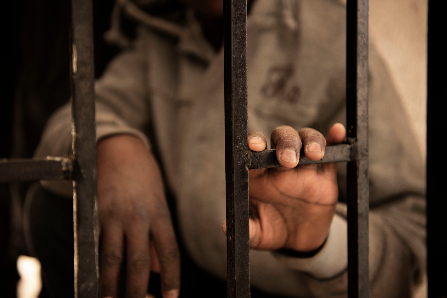 Fourteen-year-old Issaa, a migrant from Niger, rests his hand on a gate inside a detention centre, in Libya, Saturday 28 January 2017. Issaa, who has five younger others, said his mother died two years ago in Niger. I left Niger two and a half years ago, he says sitting on one of the dozens of dirty mattresses on the floor. My father collected money for my journey, he wished me good luck and then let me go. Once I arrived in Libya I started to look for a job.
