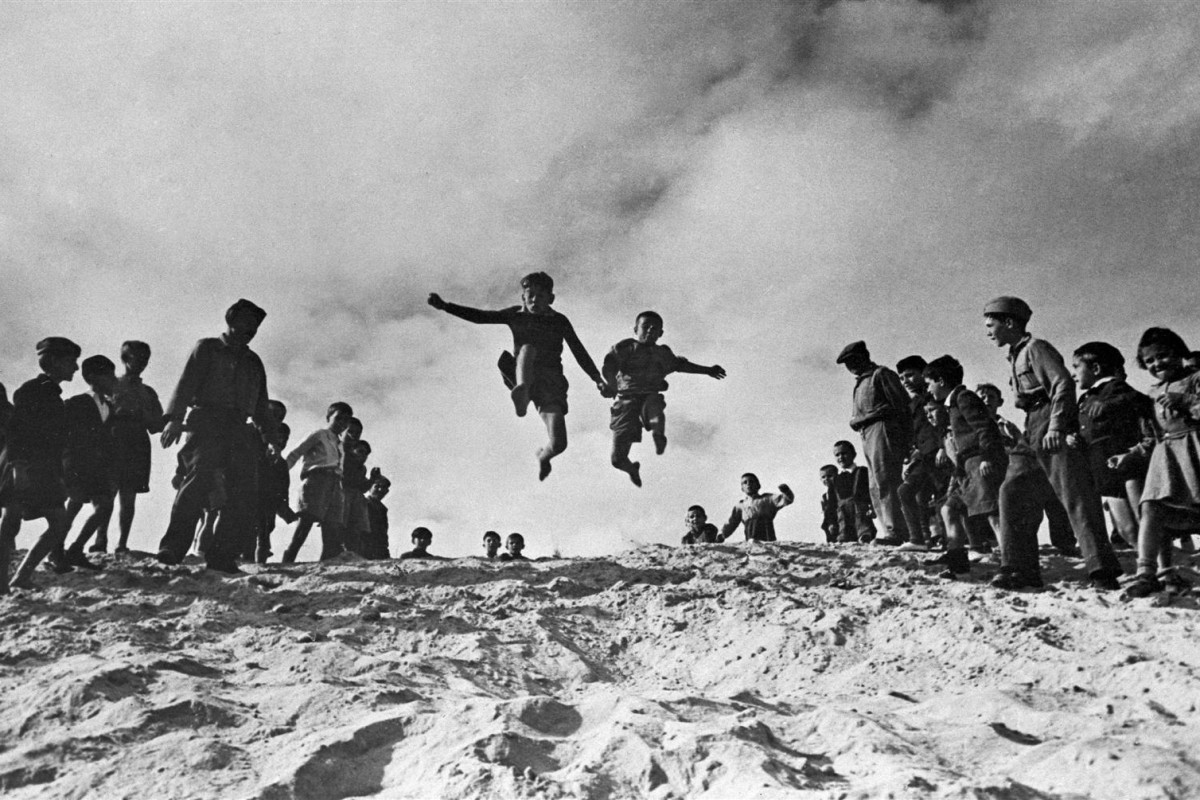 Two boys are cheered on by their companions during the long-jump event of a sports competition at the UNRRA-run El Shatt camp for Yugoslav refugees, near the north-eastern port city of Suez. Eighteen months before, these children were snipers shooting at invading German soldiers in the mountains in the Bosnian region of their country. [THIS IMAGE PROVIDED COURTESY UN ARCHIVES. INFORMATION PROVIDED TO THE EXTENT AVAILABLE.]

Circa 1947 in Egypt, 1,000 Yugoslav refugees, after assembling in the UNRRA camp division warehouse in Cairo, the capital, were sent to the northern port city of Alexandria, where some 300 were assigned to the El Shatt camp near the north-eastern port city of Suez, UNRRA's largest refugee camp in the Middle East. UNRRA, the United Nations Relief and Rehabilitation Administration, was created in 1943 to assist with relief operations and global recovery from the devastation of World War II. Focusing primarily on Europe and China, it finally closed in 1949 as its mandate was subsumed in the long-term development work of other United Nations agencies. UNRRA's work for children was taken over by UNICEF, created on 11 December 1946.